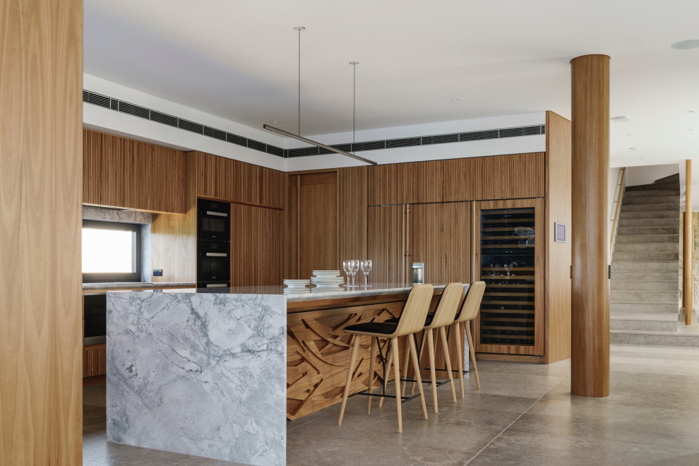 Photo of a contemporary u-shaped kitchen in Sydney with raised-panel cabinets, medium wood cabinets, marble benchtops, window splashback, panelled appliances, concrete floors, with island, grey floor and grey benchtop.