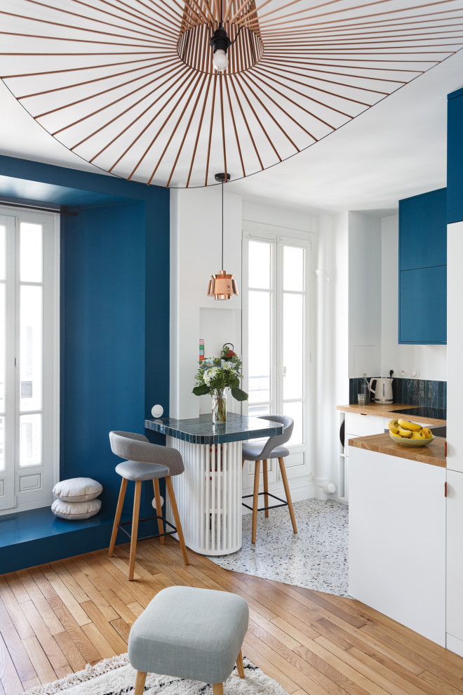 Photo of a small contemporary l-shaped open plan kitchen in Paris with a single-bowl sink, flat-panel cabinets, blue cabinets, wood worktops, blue splashback, ceramic splashback, integrated appliances, terrazzo flooring, multi-coloured floors and brown worktops.