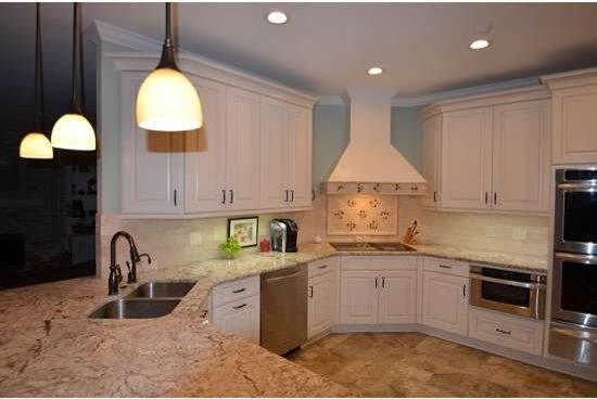 Mid-sized transitional u-shaped porcelain tile eat-in kitchen photo with an undermount sink, raised-panel cabinets, white cabinets, granite countertops, beige backsplash, ceramic backsplash, stainless steel appliances and a peninsula
