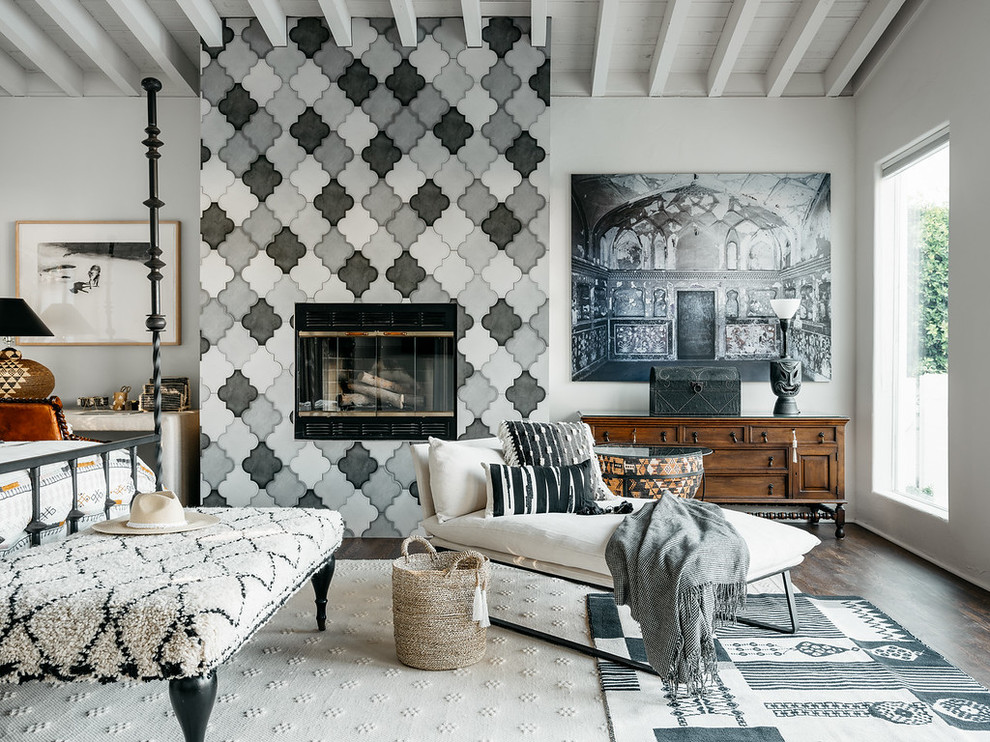 Example of a tuscan dark wood floor and brown floor bedroom design in Calgary with white walls, a standard fireplace and a tile fireplace