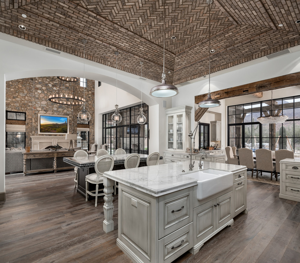 Inspiration for an expansive country u-shaped open plan kitchen in Phoenix with a farmhouse sink, raised-panel cabinets, distressed cabinets, granite benchtops, multi-coloured splashback, porcelain splashback, stainless steel appliances, medium hardwood floors, multiple islands, brown floor and multi-coloured benchtop.