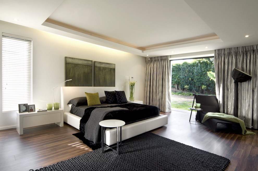 Contemporary bedroom with white walls and dark hardwood floors.