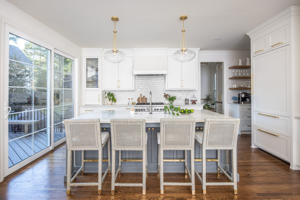 Design ideas for a mid-sized transitional open plan kitchen in Raleigh with a farmhouse sink, shaker cabinets, white cabinets, quartzite benchtops, white splashback, subway tile splashback, stainless steel appliances, medium hardwood floors, with island, brown floor and multi-coloured benchtop.