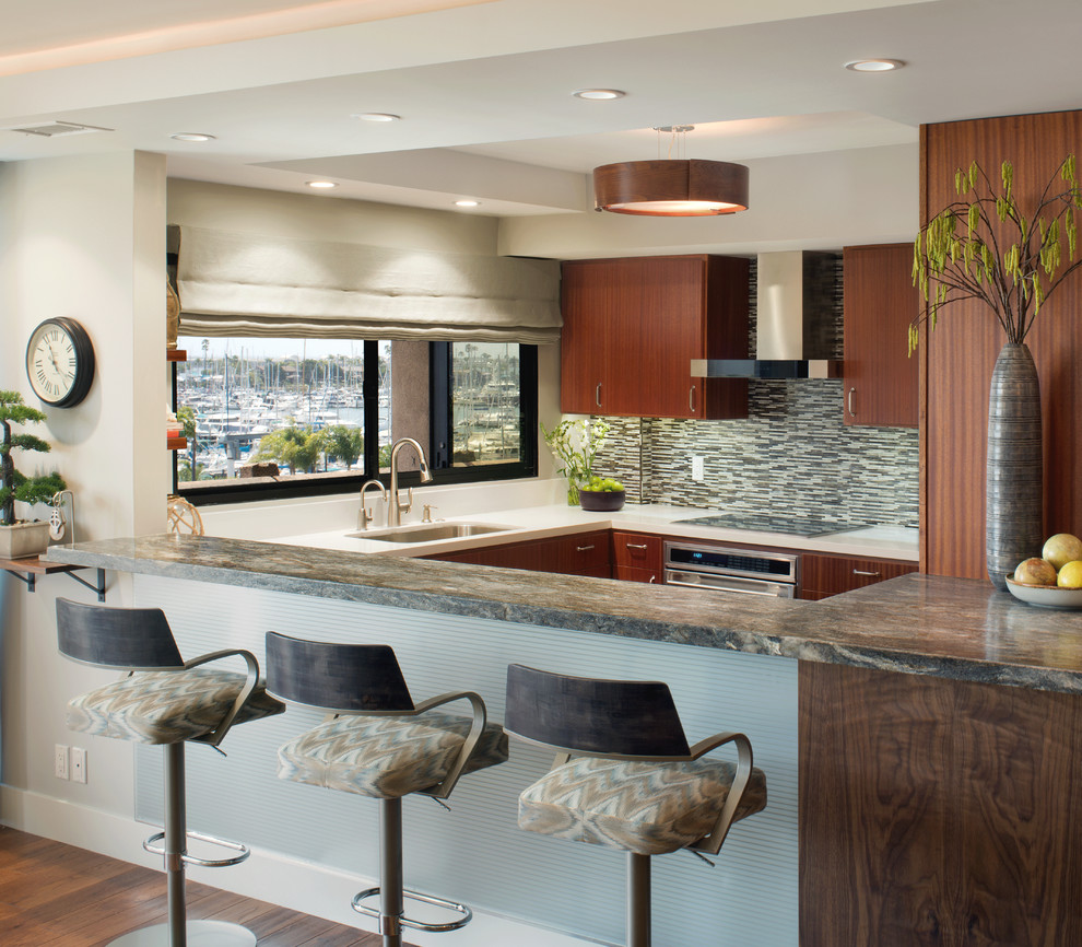 Small contemporary u-shaped open plan kitchen in San Diego with an undermount sink, flat-panel cabinets, medium wood cabinets, marble benchtops, grey splashback, glass tile splashback, stainless steel appliances and no island.