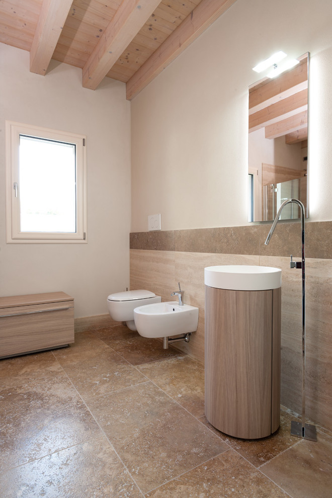 Photo of a mid-sized modern 3/4 bathroom in Other with light wood cabinets, a curbless shower, a two-piece toilet, travertine, beige walls, travertine floors, a pedestal sink, marble benchtops, brown floor, a hinged shower door and brown tile.