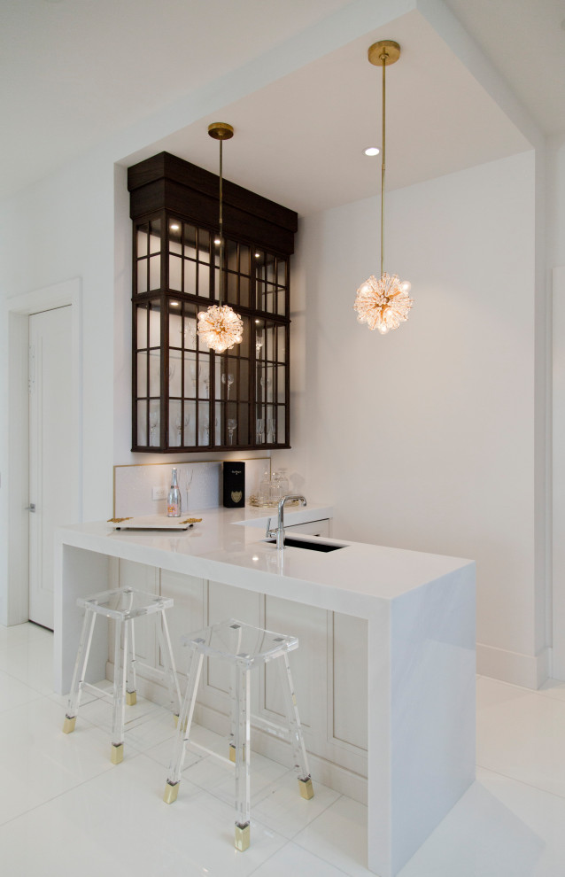 Inspiration for a mid-sized beach style l-shaped seated home bar in Miami with an undermount sink, glass-front cabinets, black cabinets, marble benchtops, white splashback, ceramic floors, white floor and white benchtop.