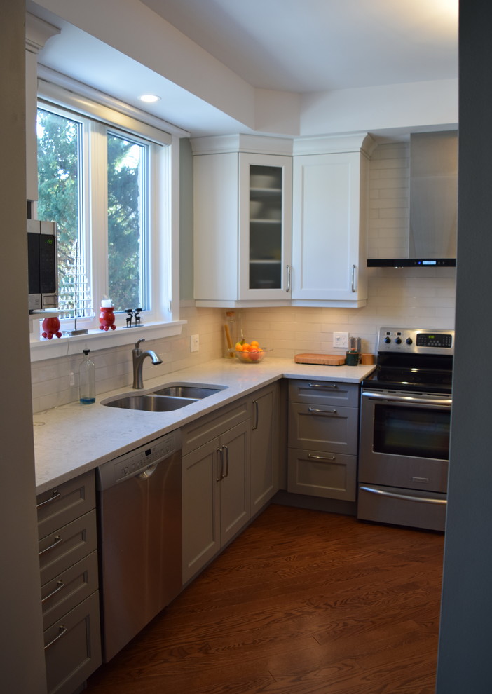 Inspiration for a mid-sized transitional l-shaped medium tone wood floor eat-in kitchen remodel in Toronto with an undermount sink, shaker cabinets, white cabinets, quartz countertops, white backsplash, subway tile backsplash, stainless steel appliances and a peninsula