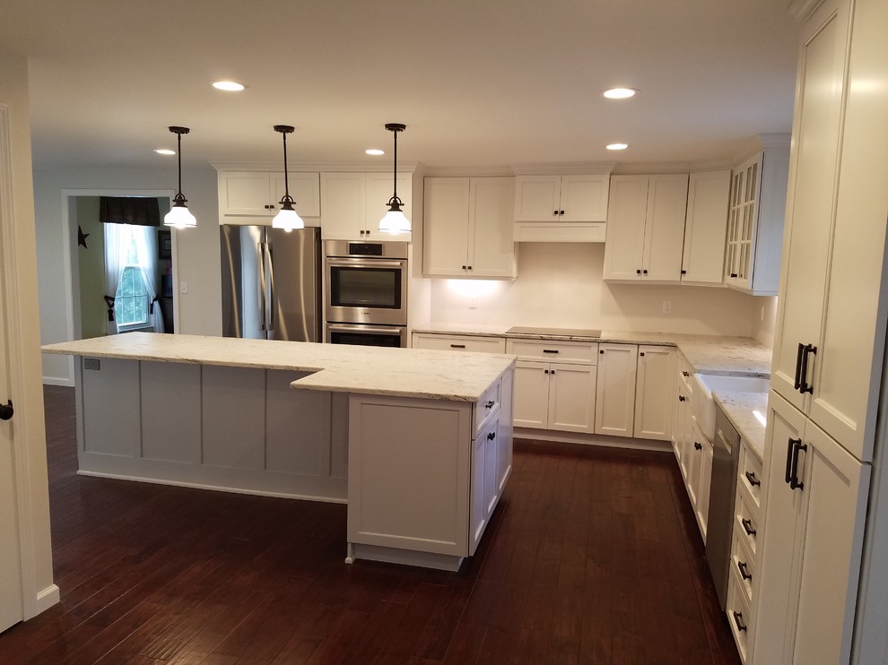 Example of a mid-sized transitional l-shaped dark wood floor and brown floor eat-in kitchen design with a farmhouse sink, shaker cabinets, white cabinets, granite countertops, white backsplash, subway tile backsplash, stainless steel appliances and an island