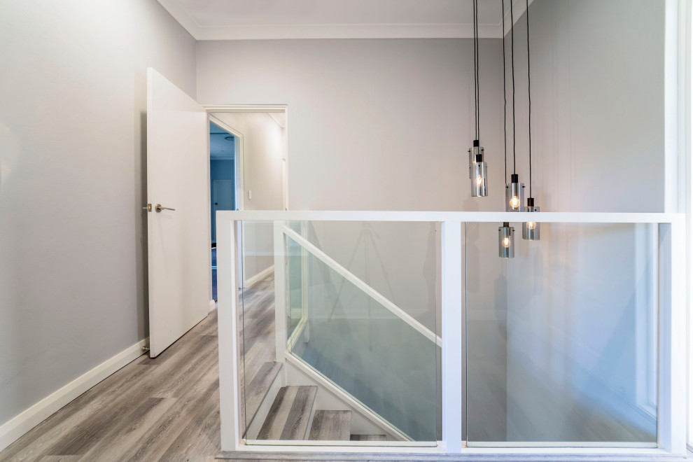 This is an example of a mid-sized contemporary acrylic u-shaped staircase in Sydney with painted wood risers and metal railing.