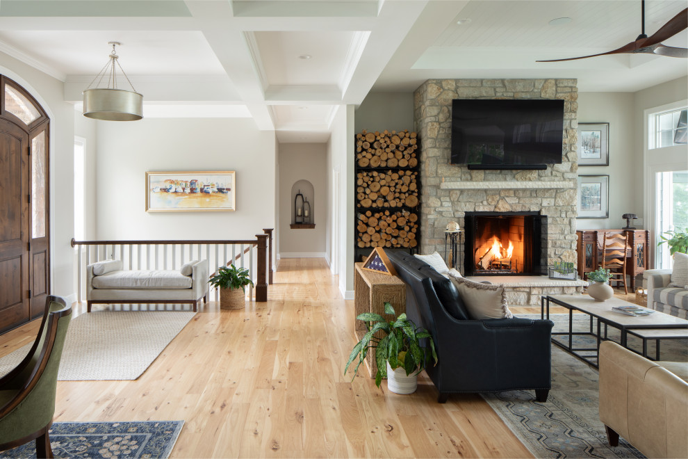 Ejemplo de salón abierto clásico renovado grande con paredes beige, suelo de madera clara, estufa de leña, marco de chimenea de piedra, suelo marrón y casetón