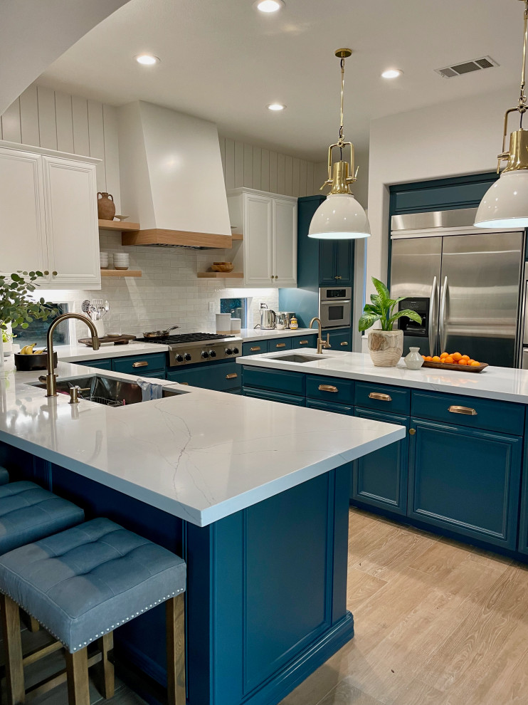 This is an example of a large traditional u-shaped enclosed kitchen in San Diego with a submerged sink, raised-panel cabinets, green cabinets, quartz worktops, white splashback, ceramic splashback, stainless steel appliances, light hardwood flooring, an island and white worktops.