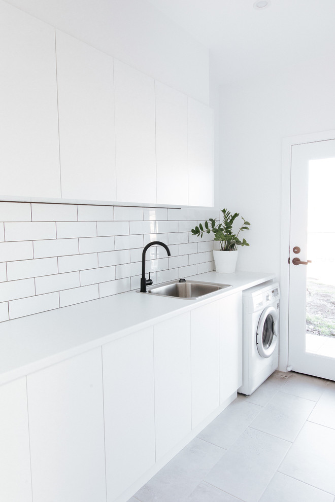 Photo of a mid-sized contemporary single-wall dedicated laundry room in Wollongong with a drop-in sink, flat-panel cabinets, white cabinets, laminate benchtops, white walls, grey floor, white benchtop and laminate floors.