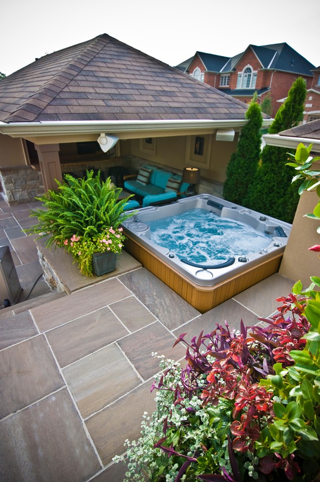 Example of a transitional backyard stone patio design in Toronto with a gazebo