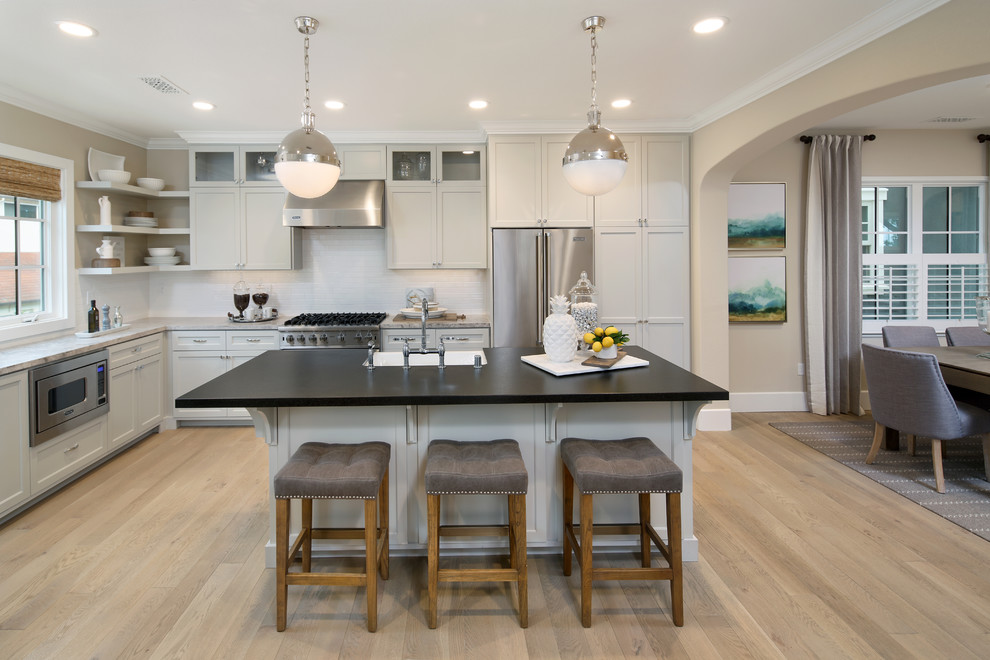 Design ideas for a transitional l-shaped eat-in kitchen in San Francisco with shaker cabinets, grey cabinets, grey splashback, stainless steel appliances, light hardwood floors and with island.