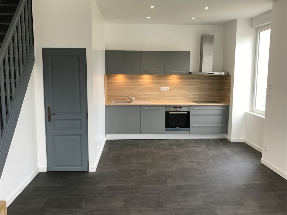 This is an example of a small contemporary single-wall open plan kitchen in Grenoble with an integrated sink, flat-panel cabinets, grey cabinets, laminate benchtops, beige splashback, stainless steel appliances, linoleum floors, no island, grey floor and beige benchtop.