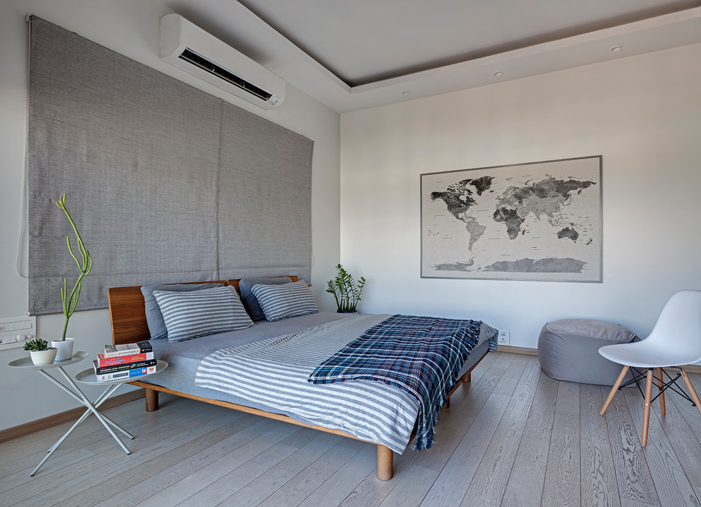 This is an example of a contemporary bedroom in Bengaluru With White Walls, Light Hardwood Floors and No Fireplace.