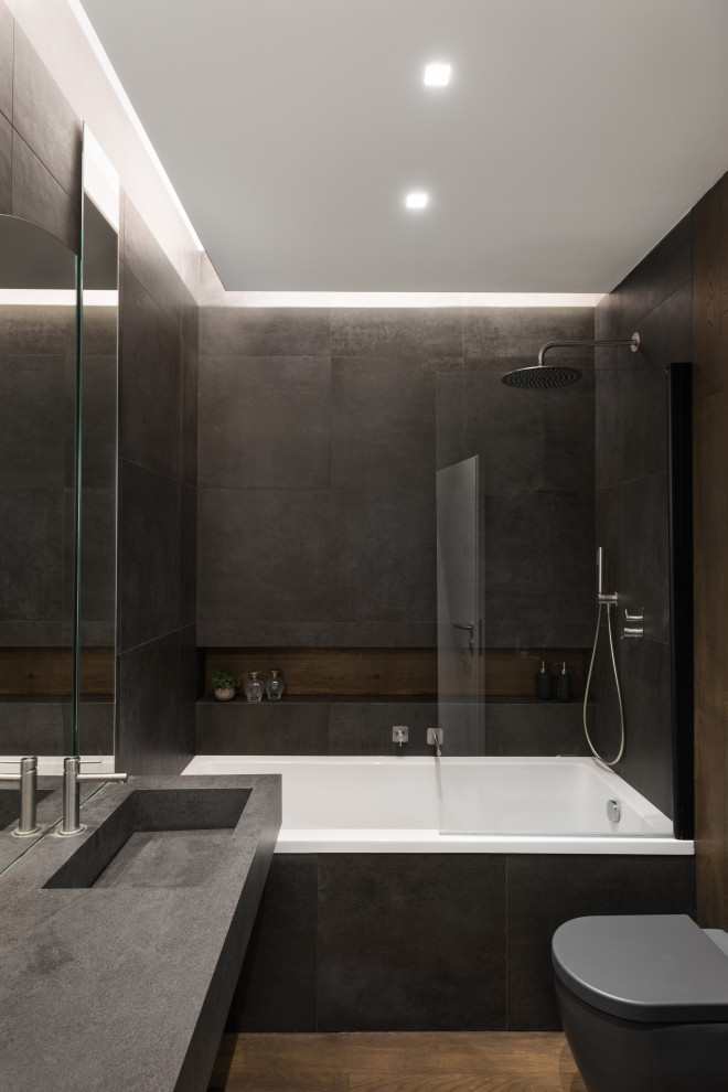 Пример оригинального дизайна: маленькая главная ванная комната в современном стиле с плоскими фасадами, серыми фасадами, накладной ванной, черной плиткой, керамогранитной плиткой, черными стенами, темным паркетным полом, накладной раковиной, столешницей из известняка, коричневым полом, серой столешницей, тумбой под одну раковину, подвесной тумбой, многоуровневым потолком и деревянными стенами для на участке и в саду