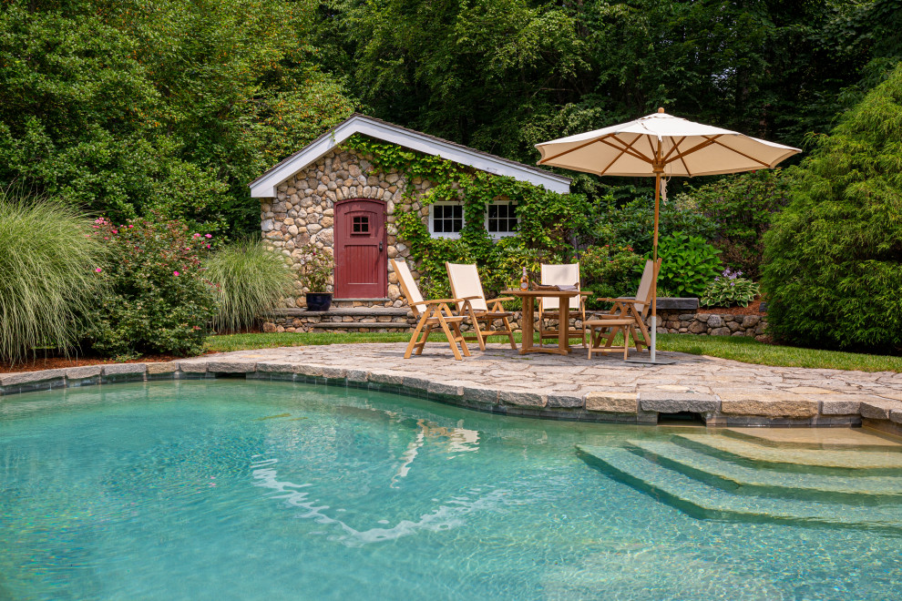 Modelo de casa de la piscina y piscina natural clásica de tamaño medio tipo riñón en patio trasero con adoquines de piedra natural