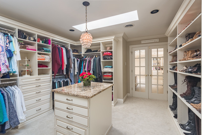 Photo of a large traditional women's dressing room in Other with raised-panel cabinets, beige cabinets and carpet.