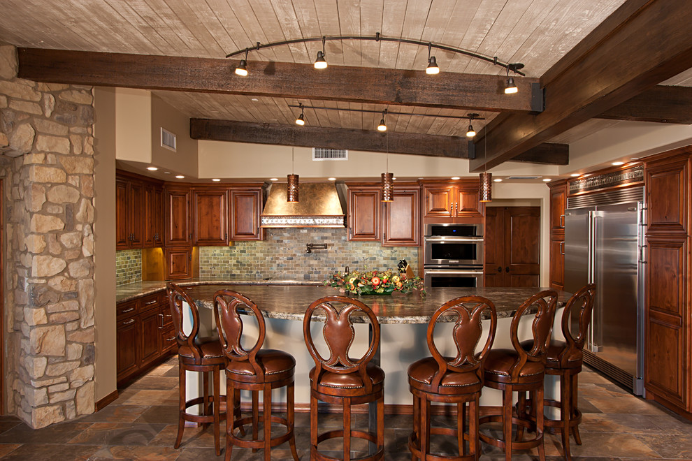 Photo of a large traditional l-shaped eat-in kitchen in Phoenix with raised-panel cabinets, medium wood cabinets, granite benchtops, grey splashback, stone tile splashback, stainless steel appliances, slate floors and with island.