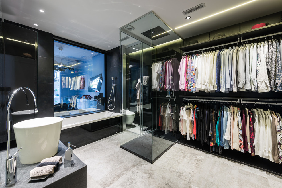 Inspiration for a mid-sized contemporary gender-neutral dressing room in Barcelona with open cabinets, black cabinets, concrete floors and grey floor.