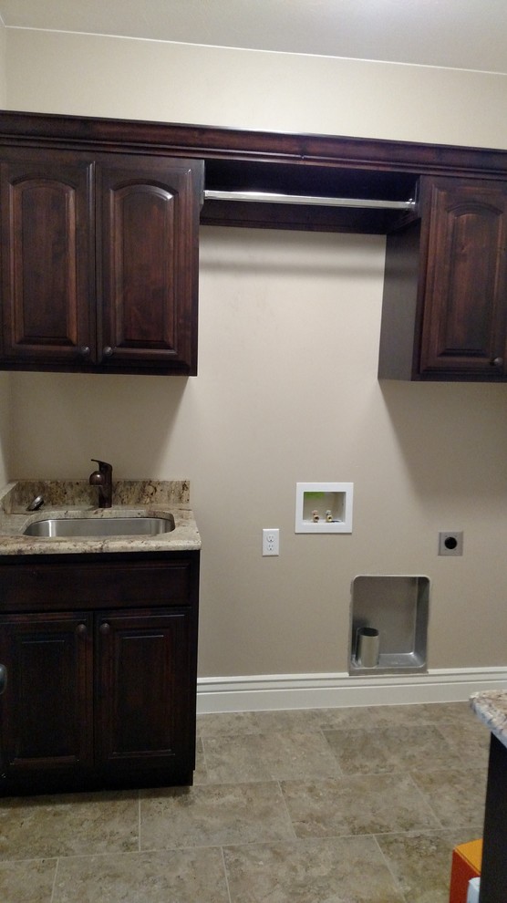 Large transitional ceramic tile dedicated laundry room photo with an undermount sink, raised-panel cabinets, dark wood cabinets, granite countertops, beige walls and a side-by-side washer/dryer