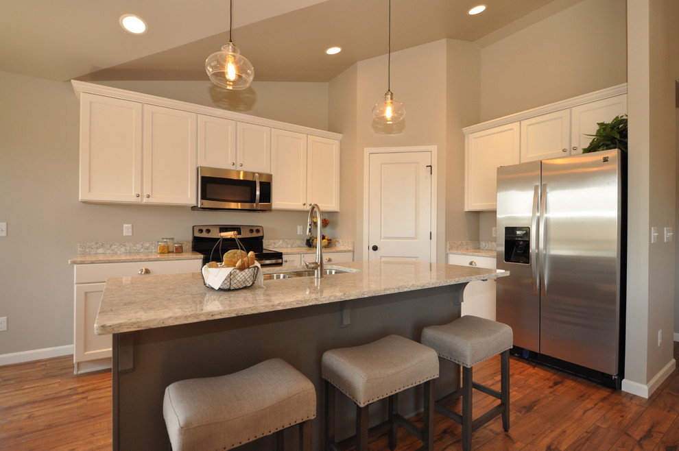 This is an example of a mid-sized arts and crafts eat-in kitchen in Milwaukee with an undermount sink, raised-panel cabinets, white cabinets, quartz benchtops, stainless steel appliances, vinyl floors and with island.