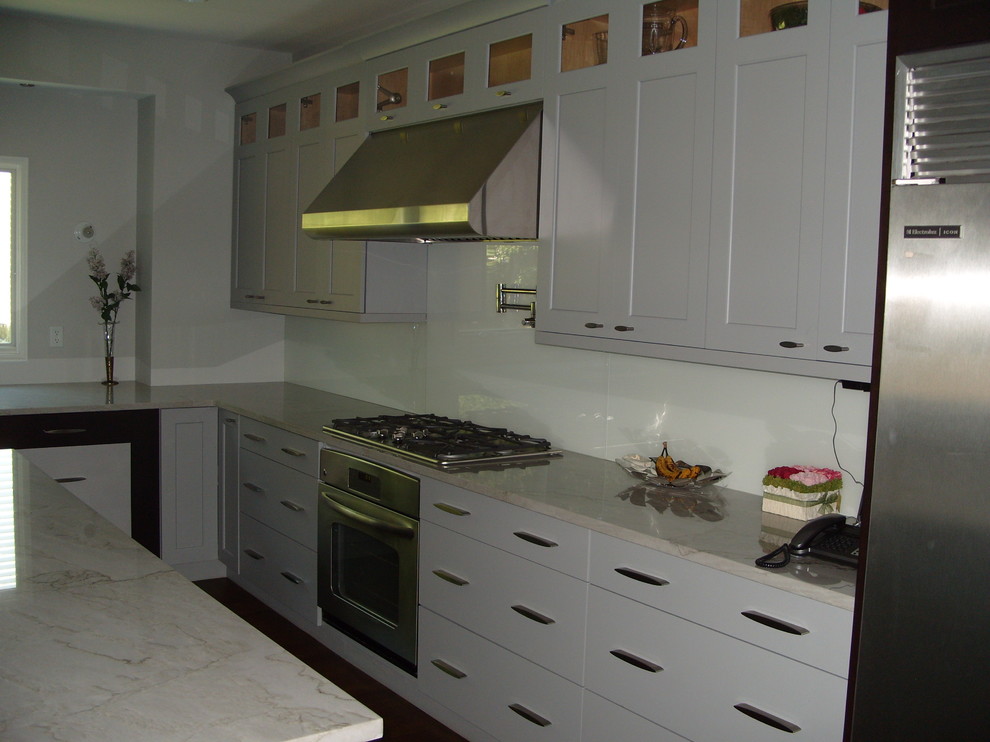 Kitchen - large transitional medium tone wood floor kitchen idea in New York with shaker cabinets, white cabinets, white backsplash, glass tile backsplash, stainless steel appliances and an island