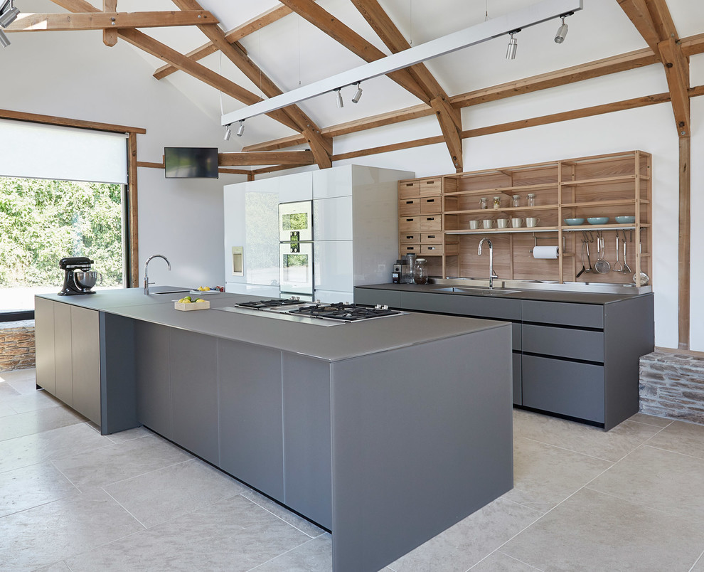 Inspiration for a large modern galley eat-in kitchen in London with a drop-in sink, flat-panel cabinets, grey cabinets, glass benchtops, brown splashback, timber splashback, stainless steel appliances, slate floors, with island, beige floor and grey benchtop.