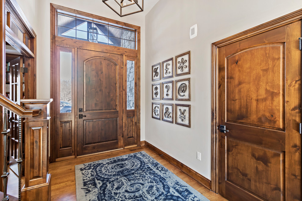 Example of a mid-sized mountain style medium tone wood floor and brown floor front door design in Charleston with beige walls and a dark wood front door