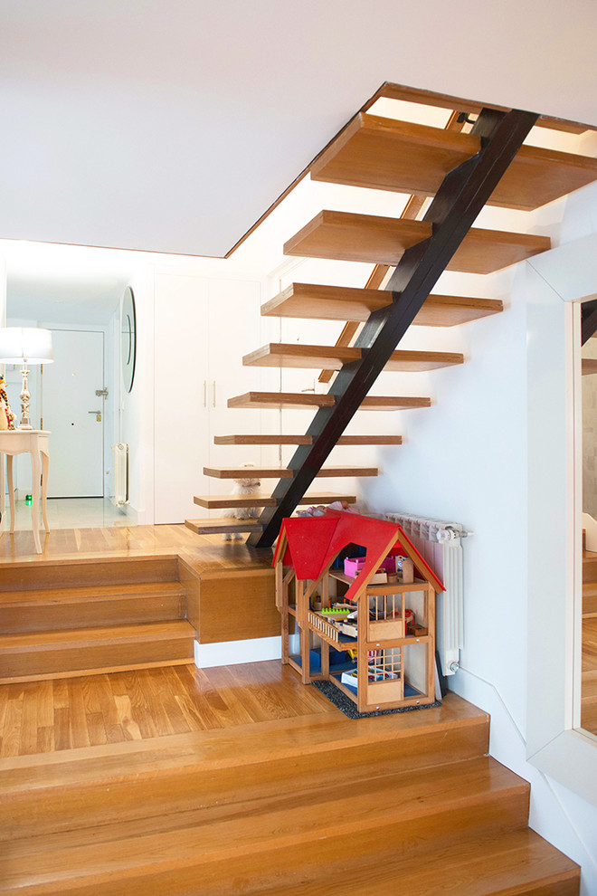 Modern wood floating staircase in Madrid with glass railing.