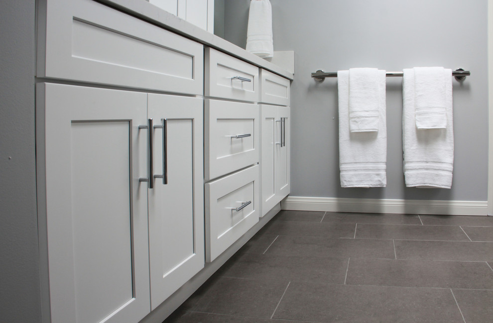Photo of a mid-sized contemporary master bathroom in Los Angeles with shaker cabinets, white cabinets, a freestanding tub, an alcove shower, a two-piece toilet, gray tile, porcelain tile, grey walls, porcelain floors, an undermount sink, engineered quartz benchtops, grey floor and a hinged shower door.
