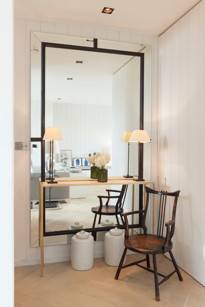 Photo of a mid-sized transitional hallway in London with white walls and light hardwood floors.