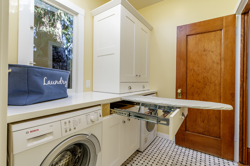 Inspiration for a mid-sized arts and crafts galley dedicated laundry room in San Francisco with shaker cabinets, white cabinets, solid surface benchtops, marble floors, a side-by-side washer and dryer, white benchtop and beige walls.