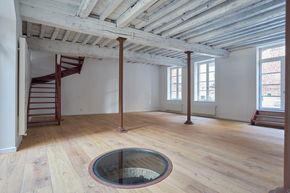 Basement - large industrial light wood floor basement idea in Lille with white walls