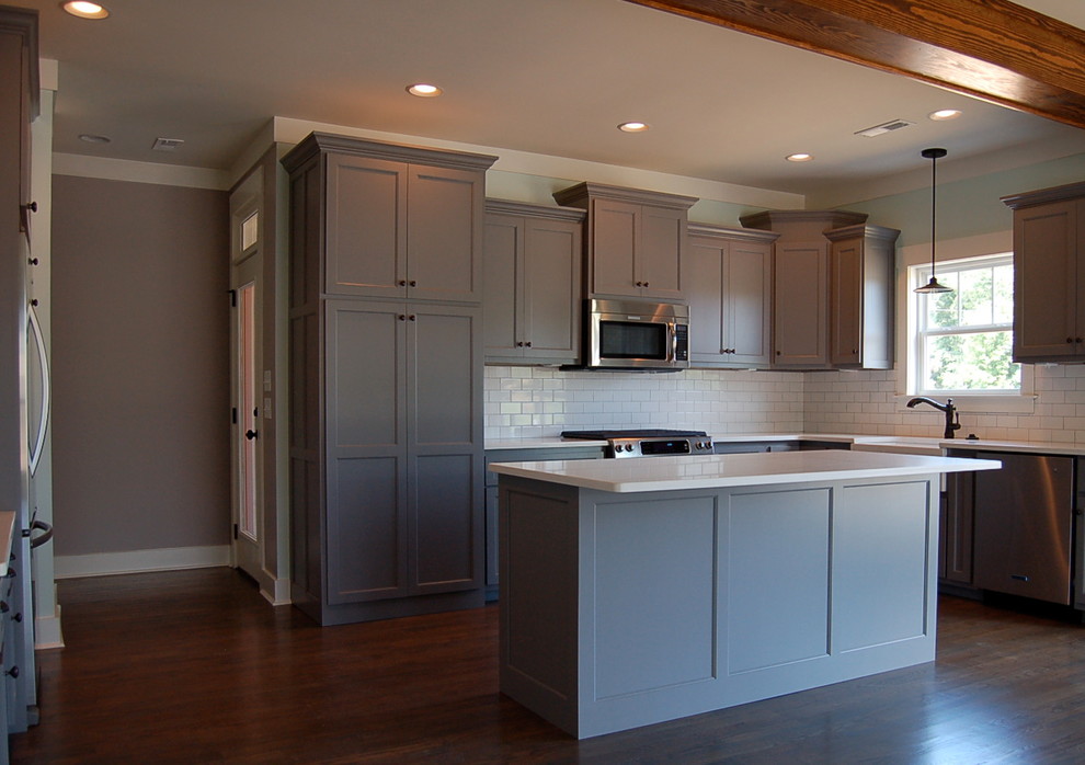 Example of a small arts and crafts l-shaped medium tone wood floor eat-in kitchen design with shaker cabinets, gray cabinets, granite countertops, white backsplash, subway tile backsplash, stainless steel appliances, blue walls and an island
