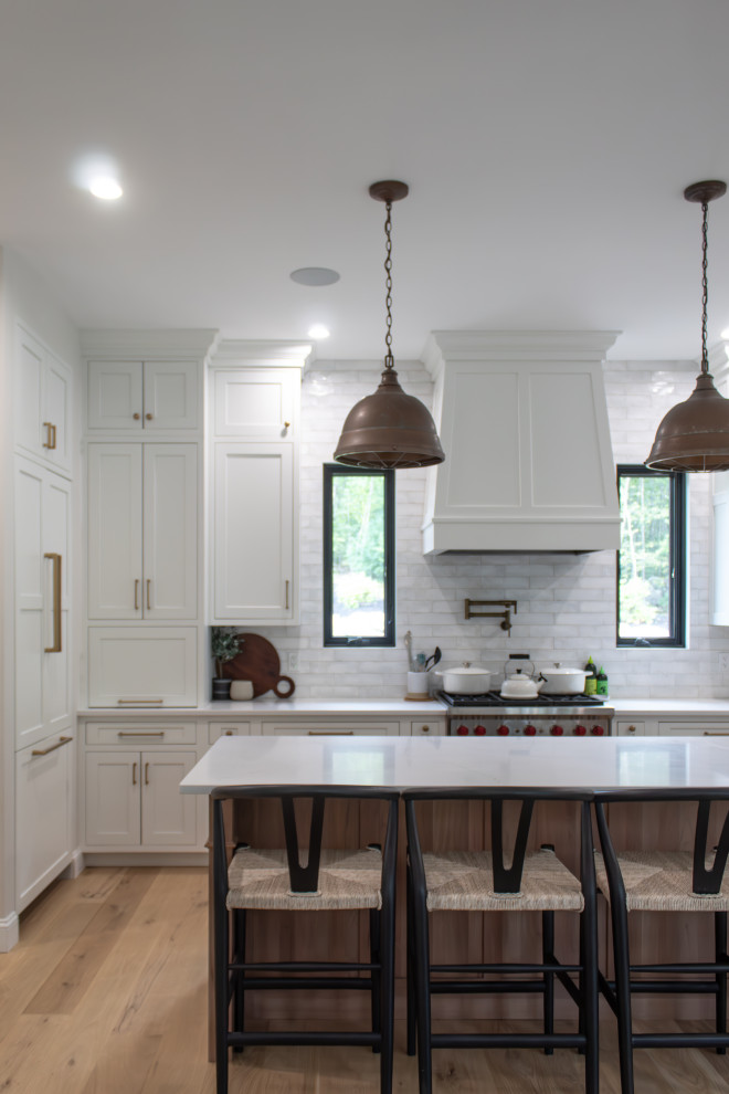 Design ideas for a large transitional l-shaped eat-in kitchen in Boston with beaded inset cabinets, white cabinets, quartz benchtops, white splashback, panelled appliances, light hardwood floors, with island, beige floor and white benchtop.