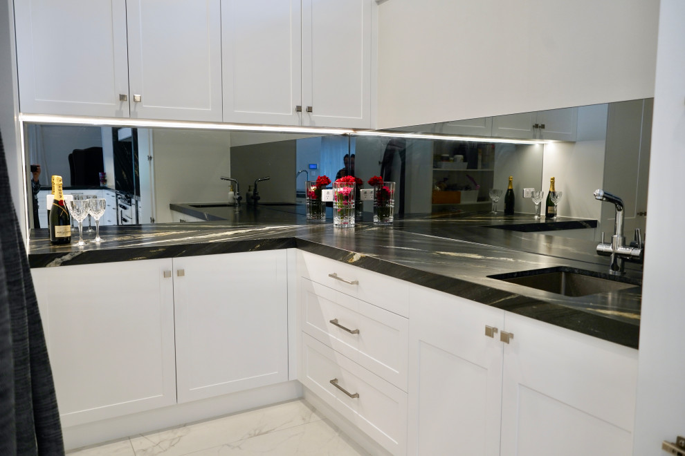 Immagine di un'ampia cucina moderna con lavello sottopiano, ante in stile shaker, ante bianche, top in marmo, paraspruzzi grigio, paraspruzzi a specchio, elettrodomestici bianchi, pavimento in gres porcellanato, pavimento bianco, top nero e soffitto ribassato