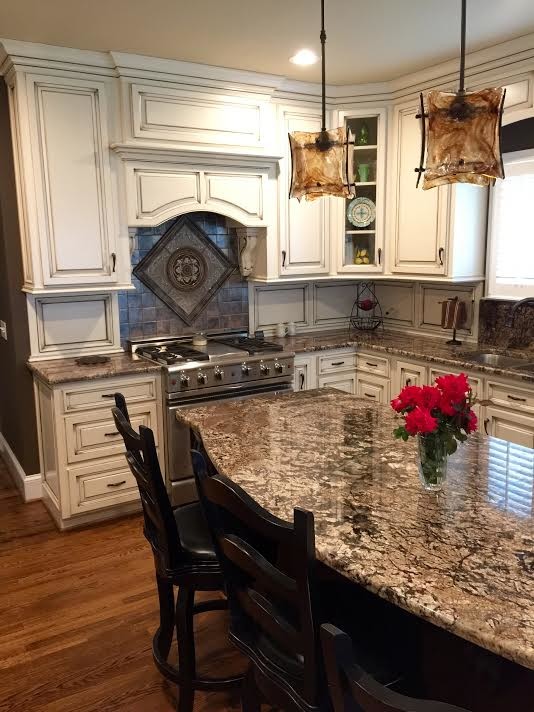 Mid-sized transitional l-shaped medium tone wood floor and brown floor eat-in kitchen photo in Birmingham with a double-bowl sink, raised-panel cabinets, white cabinets, multicolored backsplash, stainless steel appliances and an island