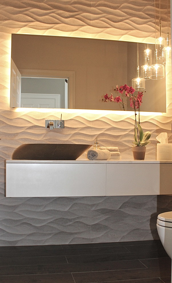 Photo of a small modern powder room in Boston with flat-panel cabinets, beige cabinets, gray tile, porcelain tile, grey walls, porcelain floors and a vessel sink.