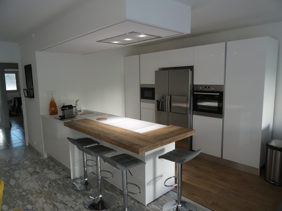 Inspiration for a mid-sized modern galley open plan kitchen in Marseille with an undermount sink, beaded inset cabinets, white cabinets, laminate benchtops, stainless steel appliances, marble floors, with island and grey floor.
