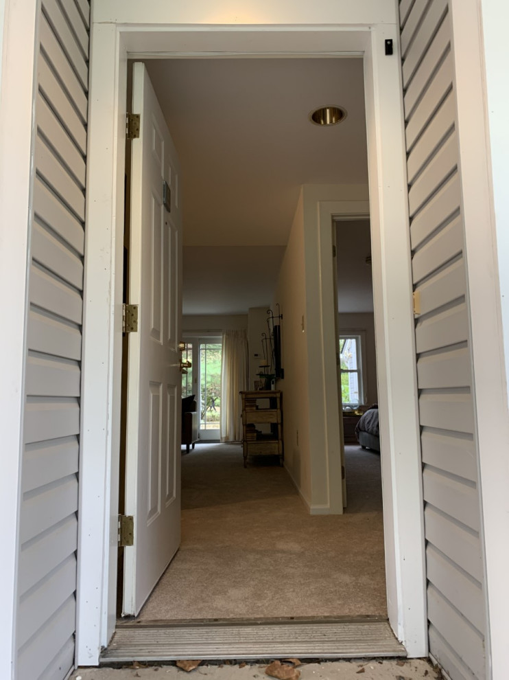 This is an example of a small transitional front door in Philadelphia with white walls, a single front door and a brown front door.