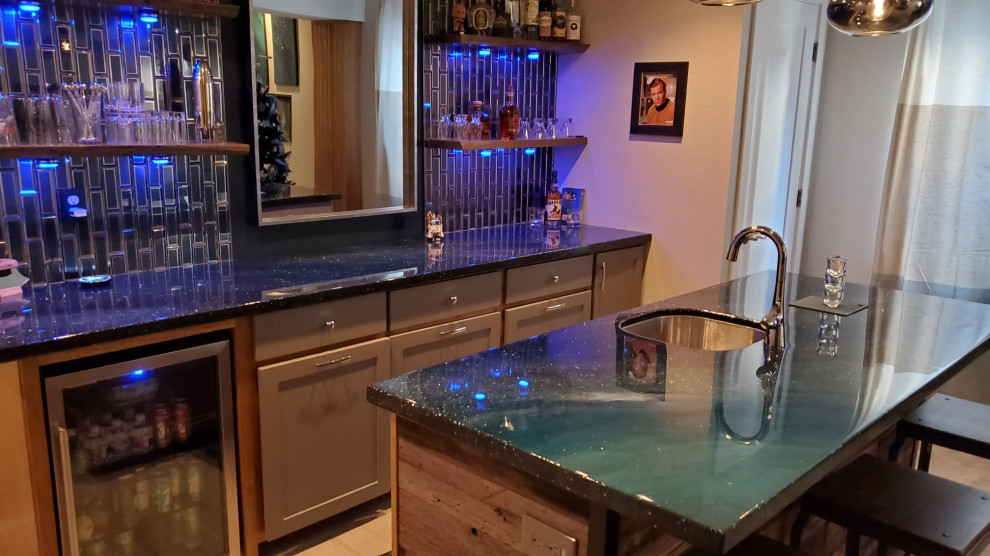 Photo of a mid-sized modern galley wet bar in Denver with an undermount sink, recessed-panel cabinets, grey cabinets, blue splashback, glass tile splashback, ceramic floors, grey floor and blue benchtop.