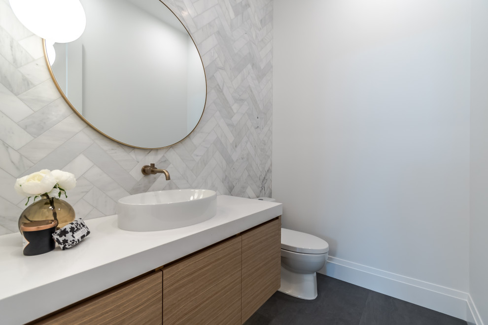 Photo of a large scandi cloakroom in Vancouver with flat-panel cabinets, light wood cabinets, a one-piece toilet, white tiles, marble tiles, white walls, porcelain flooring, a vessel sink, engineered stone worktops, grey floors, white worktops and a floating vanity unit.