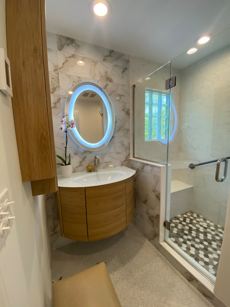 На фото: маленькая главная ванная комната в стиле модернизм с фасадами островного типа, светлыми деревянными фасадами, душем в нише, раздельным унитазом, бежевой плиткой, керамогранитной плиткой, белыми стенами, полом из керамогранита, монолитной раковиной, стеклянной столешницей, бежевым полом, душем с распашными дверями, белой столешницей, сиденьем для душа, тумбой под одну раковину и подвесной тумбой для на участке и в саду