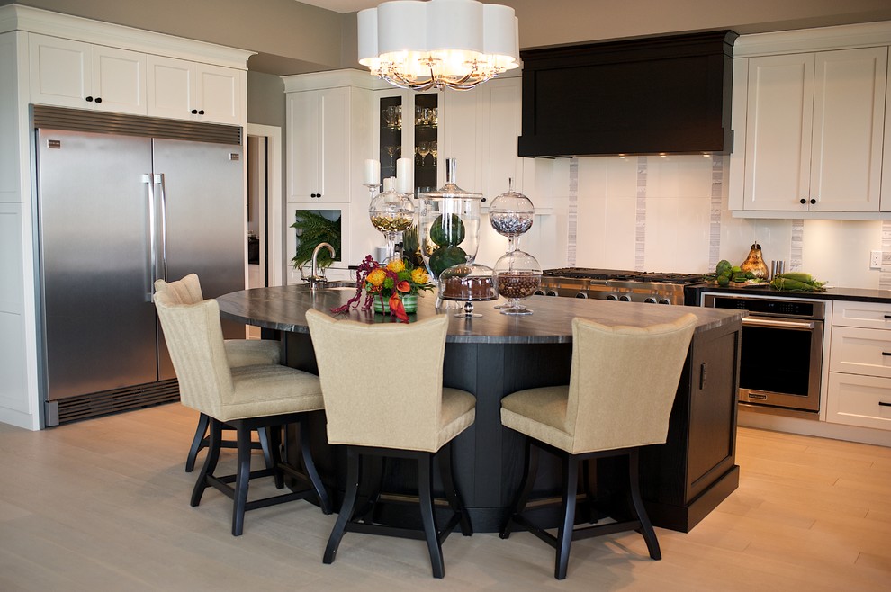Example of a large transitional u-shaped light wood floor eat-in kitchen design in Edmonton with a farmhouse sink, shaker cabinets, white cabinets, granite countertops, white backsplash, stone tile backsplash, stainless steel appliances and an island