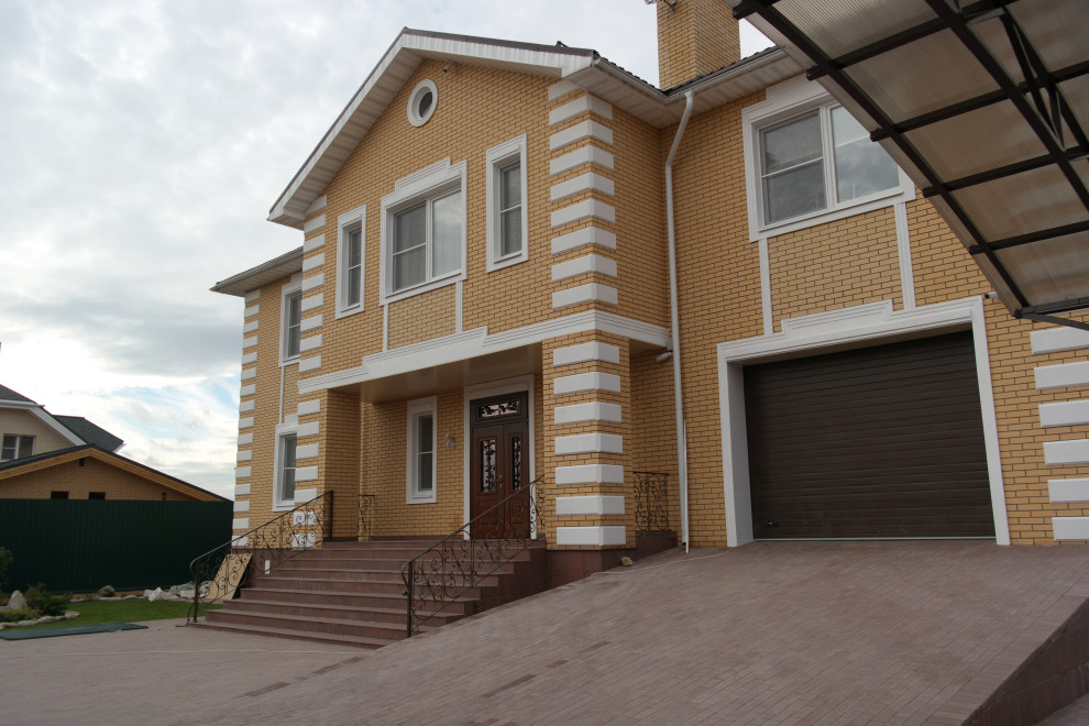 На фото: двухэтажный, кирпичный, оранжевый частный загородный дом среднего размера с двускатной крышей и металлической крышей