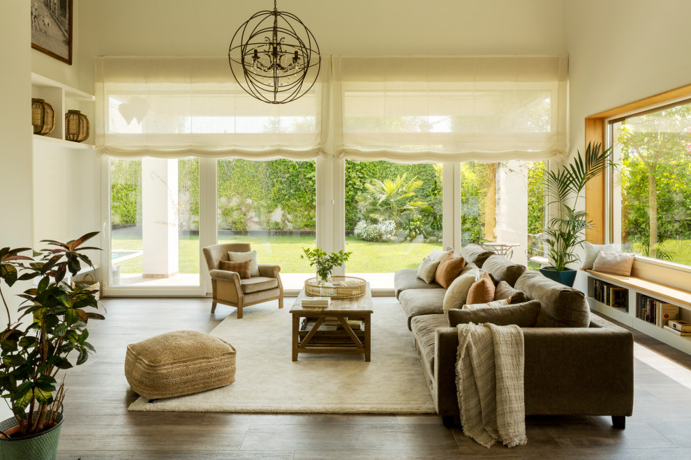 Inspiration for a mid-sized mediterranean open concept living room in Barcelona with white walls, medium hardwood floors, a ribbon fireplace, a plaster fireplace surround, no tv and brown floor.