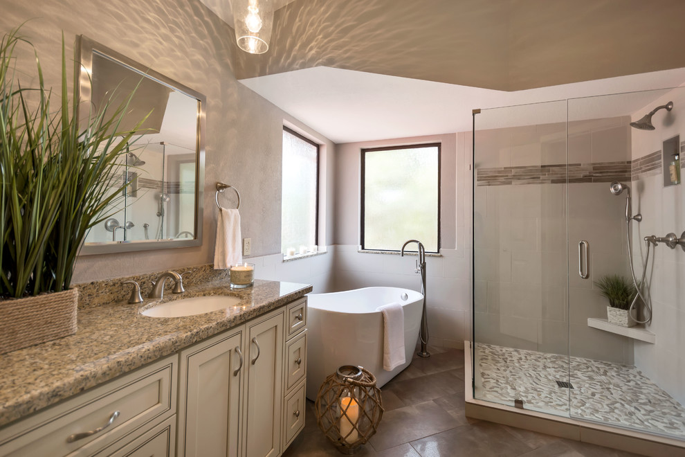Large contemporary master bathroom in Phoenix with beaded inset cabinets, white cabinets, a freestanding tub, a corner shower, a two-piece toilet, brown tile, porcelain tile, grey walls, porcelain floors, an undermount sink and granite benchtops.