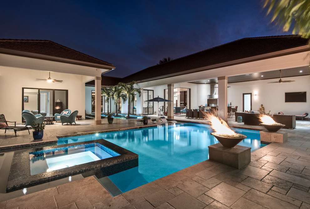 Inspiration for a large transitional backyard custom-shaped pool in Miami with a water feature and natural stone pavers.